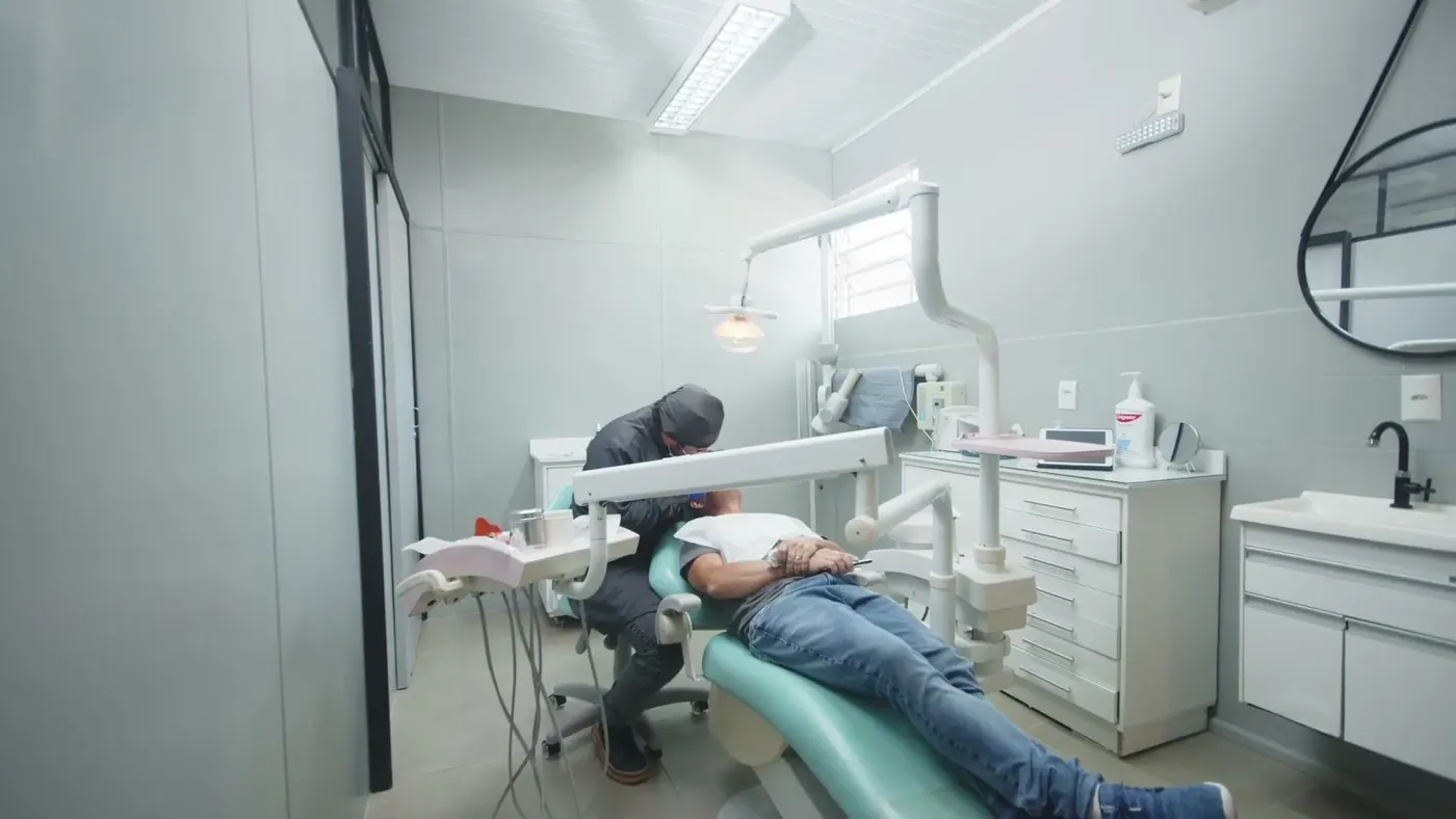 Consultório da Crídente durante um atendimento: cadeira verde-água, refletor aceso e bancada branca